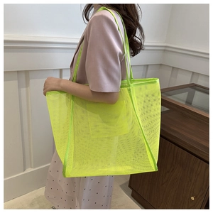 Detail of neon green large mesh tote bag showing translucent material and woven handle