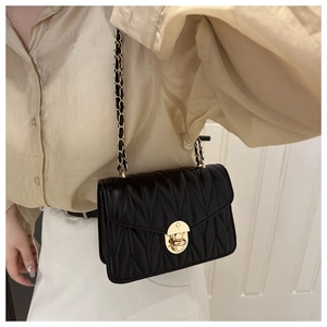 Detail of black quilted shoulder bag with gold twist lock and leather woven chain strap