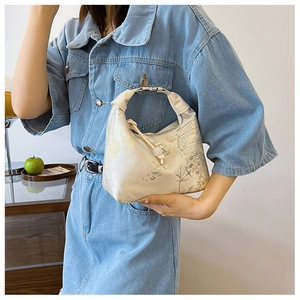 Detailed shot of cream satin dumpling bag featuring elegant Chinese floral embroidery