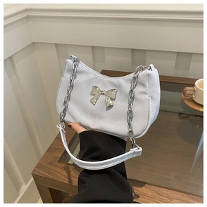 Detailed shot of a soft blue crescent underarm bag with a silver metal bow and chain