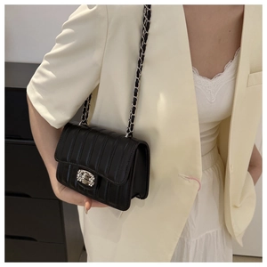Detail of black crossbody bag with vertical stitching and sparkling diamond swivel lock