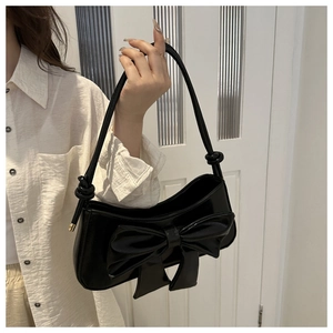 Detailed view of black PU shoulder bag with oversized bow and elegant gold metal accents