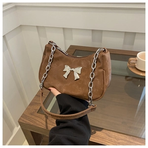 Detail of vintage brown shoulder bag showing silver bow ornament and chain strap