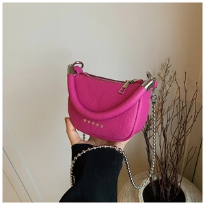 Detail of rose pink litchi leather mini saddle bag with gold star studs and bead chain