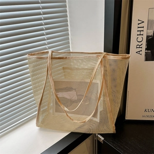 Minimalist beige mesh tote bag with reinforced straps displayed in a bright sunny room