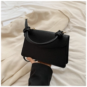 Detail of black lychee grain leather handbag featuring a stylish knotted top handle