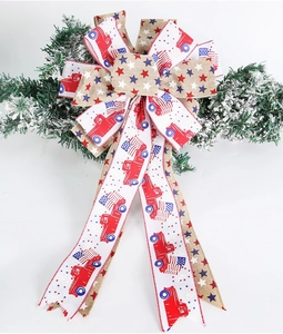 Detail of USA Independence Day burlap bow with stars and stripes hanging on a pine branch