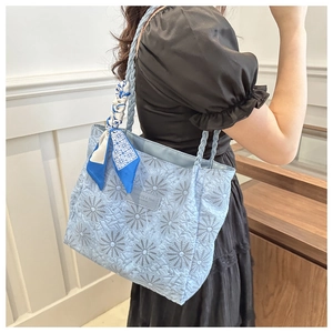 Detailed view of light blue tote bag featuring sunflower texture and floral silk scarf handle