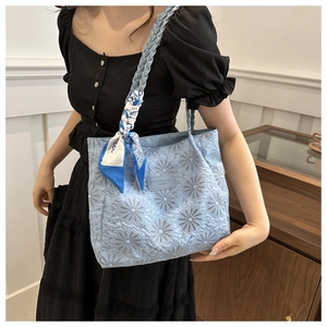 Detail of light blue quilted tote bag with daisy embroidery and decorative silk scarf