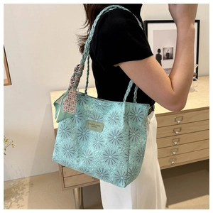 Detail of mint green tote bag with daisy print, silk scarf, and woven handles on model