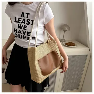 Détail d'un sac cabas en paille tressée avec poche en cuir marron et anses en corde de coton