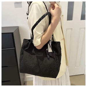 Detail of black pleated textured tote bag with thick woven handle and floral silk scarf