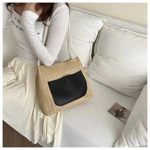 Détail d'un sac cabas en paille avec poche noire et anses en corde de coton blanc