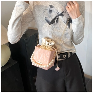 Detail of pink pleated leather bucket bag featuring pearl handle and gold chain strap