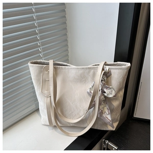 Gros plan du sac cabas beige avec texture marbrée et foulard décoratif à imprimé