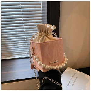 Detailed shot of pink bucket bag featuring marble texture and elegant pearl handle