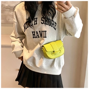 Détail du sac selle en cuir grainé jaune citron avec bandoulière chaîne sur modèle