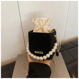 Detail of black quilted bucket bag with pearl handle and cream drawstring pouch