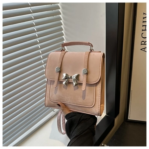 Detalle de mochila de ante rosa con lazo de mariposa plateado y correas decorativas