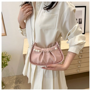 Detail of pink satin cloud bag featuring large pearl chain and silver strap over soft casual dress