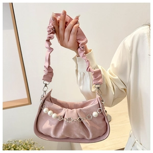 Close-up of pink pleated handbag featuring large pearls and floral metal chain detail