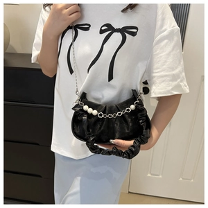 Detail of black pleated cloud bag featuring pearl chain and floral metal accents