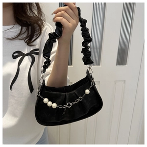 Detail of black pleated shoulder bag featuring elegant pearl accents and floral metal buckle