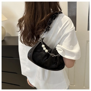 Detail of black ruched handbag with pearl chain and silk-like pleated finish on shoulder