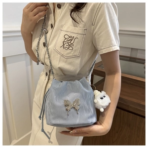 Detailed view of light blue drawstring bucket bag with silver butterfly and plush charm