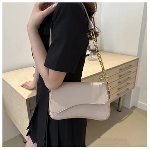 Close-up of the beige shoulder bag with unique wavy flap and chunky gold chain strap