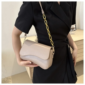 Detail of light beige PU leather shoulder bag with decorative gold chain strap on model