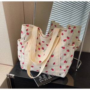 Detail view of strawberry print corduroy tote bag featuring multiple storage pockets