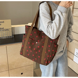 Lifestyle shot of brown corduroy tote bag with strawberry print and snap pocket