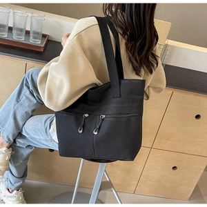 Close-up of black canvas tote bag with functional dual parallel front zipper pockets