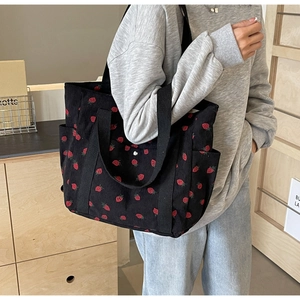 Detail of strawberry print corduroy tote bag showing large capacity and side pocket