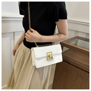 Minimalist white shoulder bag with gold chain strap and geometric hardware detail