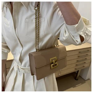 Détail d'un sac à bandoulière en cuir beige avec fermoir doré vintage et chaîne fine