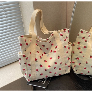 Detail of strawberry print corduroy tote bag featuring side pockets and reinforced straps