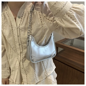 Silver metallic hobo underarm bag with metal chain strap worn on a beige lace shirt