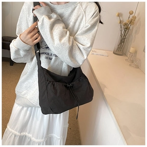 Close-up of black nylon tote bag with drawstring pleated design and wide strap