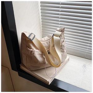 Detail of beige nylon crossbody tote bag with adjustable strap and side pocket design