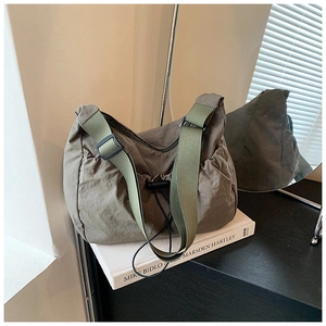 Detailed macro view of olive green crinkled nylon tote bag on a white book prop