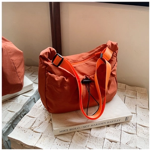 Detail of orange tote bag with drawstring closure and bright orange textile shoulder strap