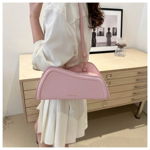 Detail of light pink asymmetric leather shoulder bag with golden buckles and minimalist logo