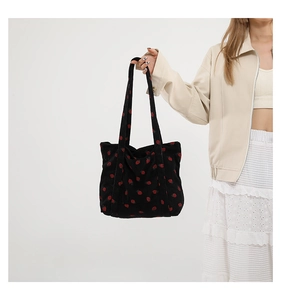 Close-up of black corduroy tote bag with strawberry print and soft ribbed texture