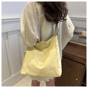 Dettaglio della borsa tote gialla chiara minimalista indossata da una modella in una stanza