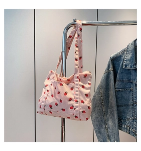 Detailed texture of pink corduroy tote bag featuring red strawberry patterns on a hanger