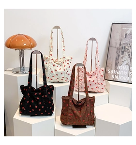 Detail of four colorful strawberry print corduroy tote bags on geometric displays