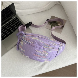 Detail of purple seersucker crossbody bag with colorful stitching on a white sofa