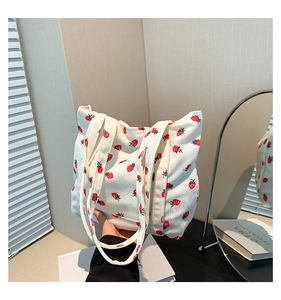 Detail of white corduroy tote bag with red strawberry pattern and soft texture